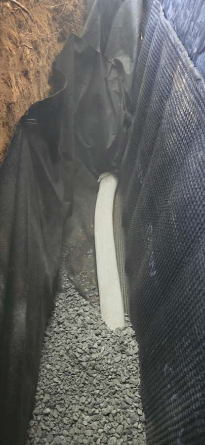 Foundation-drain pipe and clean stone placed beside an exterior waterproofing membrane