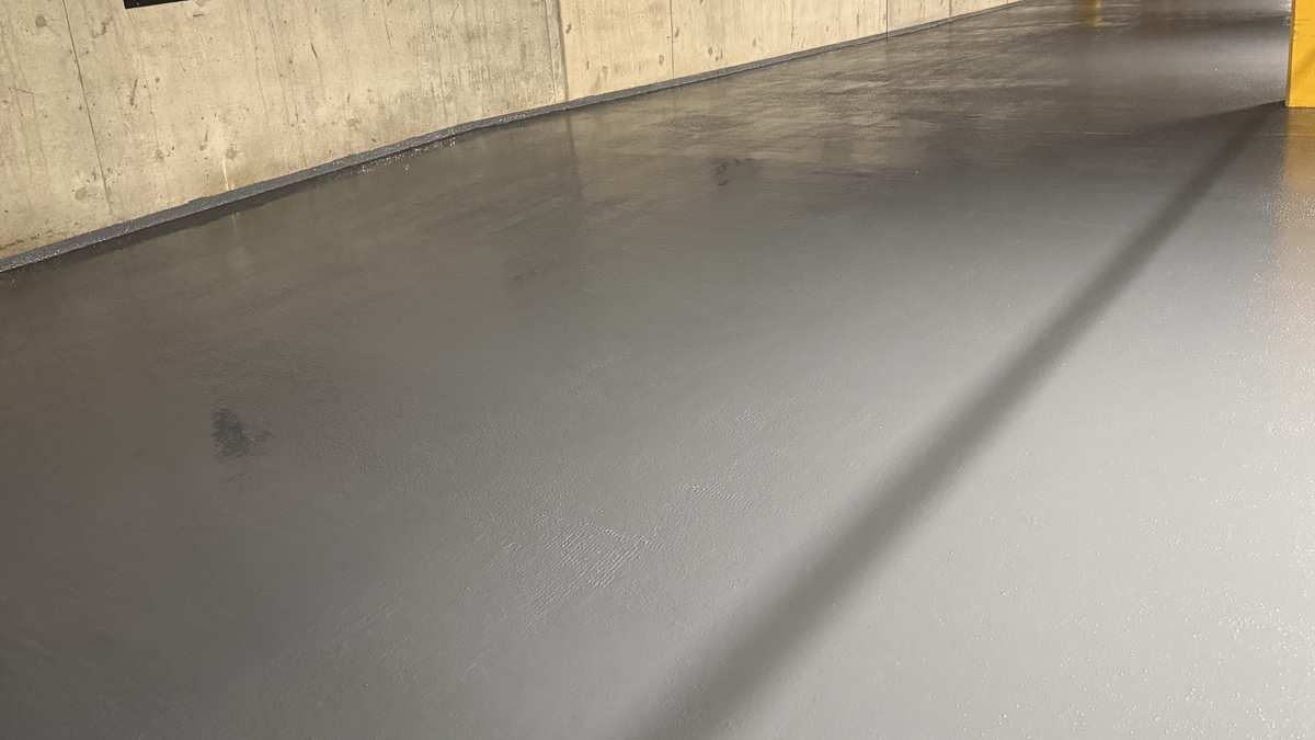 Completed gray traffic surface across a repaired parking garage floor section