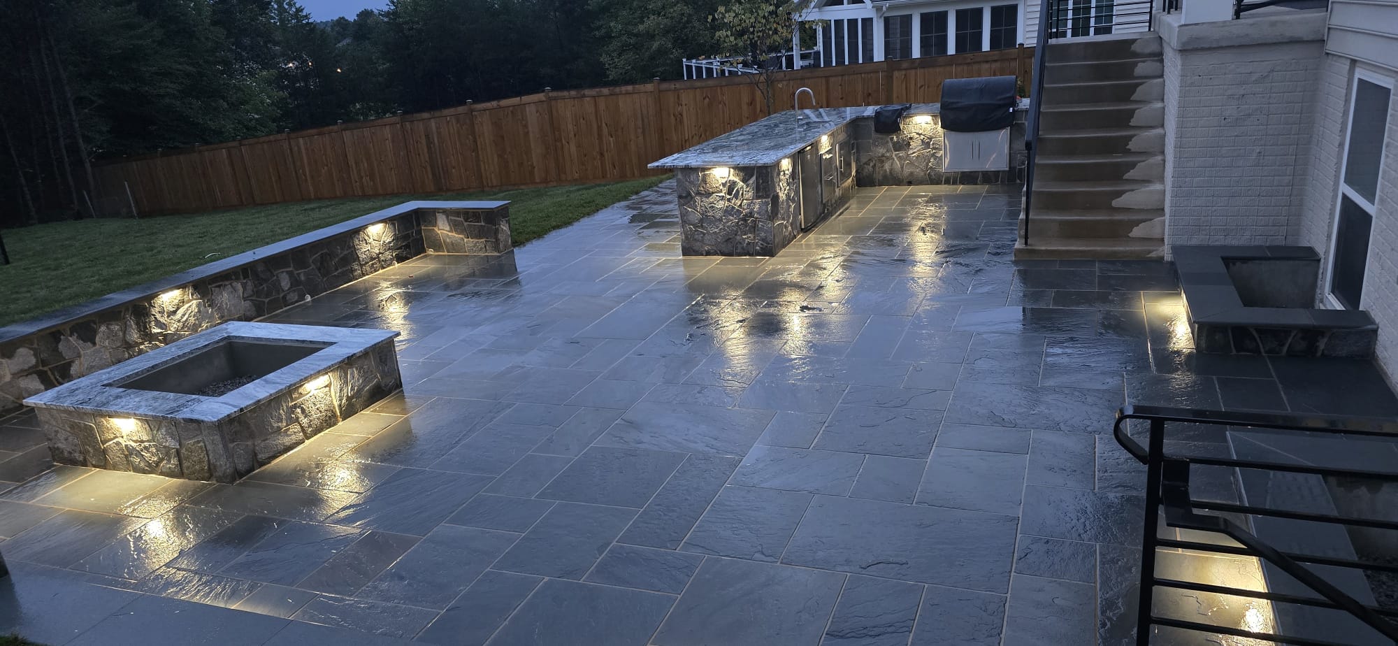 Illuminated stone patio and outdoor kitchen